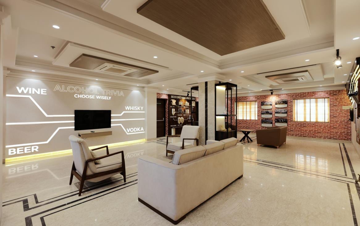 Staff lounge with a backlit graphic feature wall, wall-mounted TV, accent chair, sofa and exposed-brick niche.