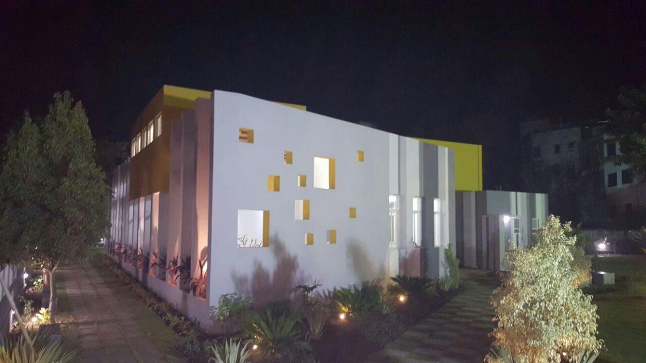 Night view of the white Vithaldeo Library facade punctuated by brightly coloured projecting window boxes.