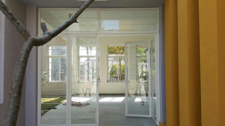 Glazed reading-room entrance with full-height glass doors and an orange curtain, a tree visible beyond.